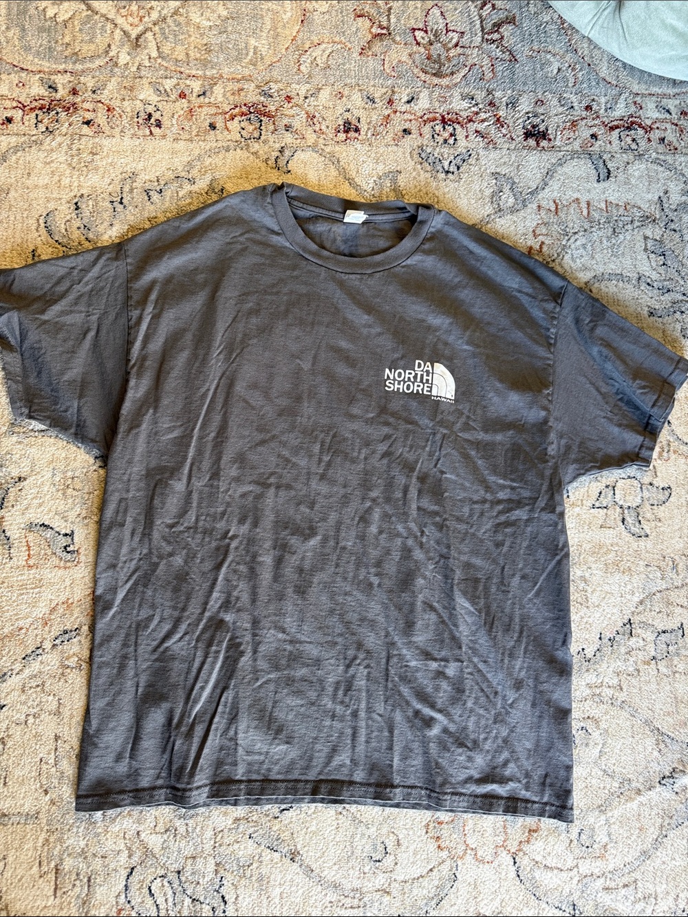 The North Face featuring a white "DA NORTH SHORE HAWAI'I" logo on the chest.
